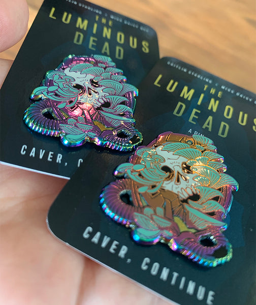 Image of the rainbow metal glowing skull pins at an angle to show the smooth epoxy surface and the variety in anodized metal coloration.